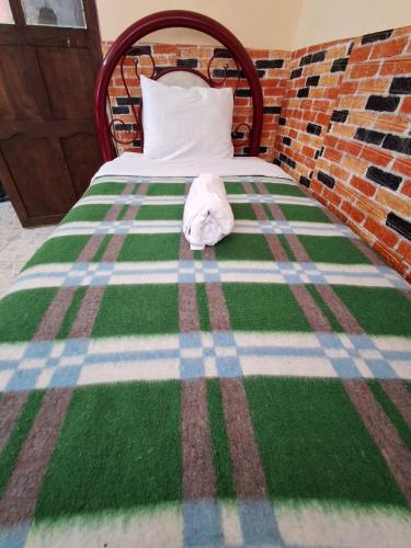 a bed with a green and white blanket on it at Backpackers Oruro B&B in Oruro