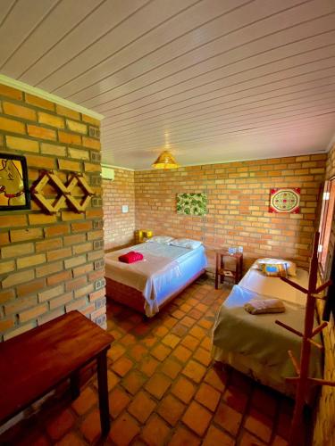 a room with two beds and a brick wall at Pousada Da Bell in Barreirinhas