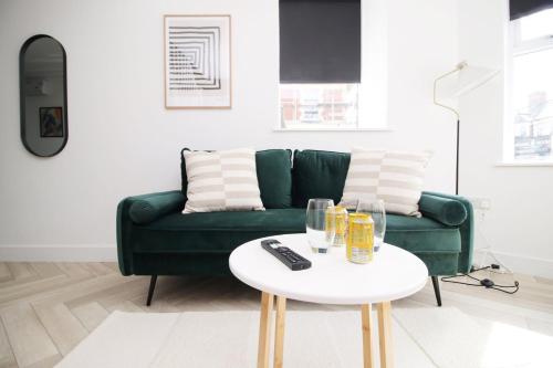 sala de estar con sofá verde y mesa blanca en Centrally Located 2 Bedroom, en Cardiff
