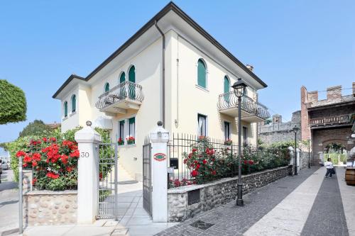 a white building with red flowers and a street light at Hotel Villa Cansignorio in Lazise