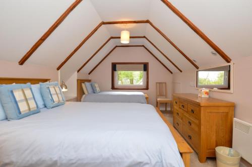 two beds in a room with two windows at Birch Cottage in Blairmore