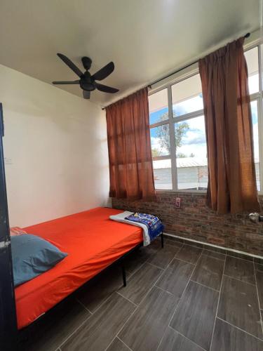 - une chambre avec un lit et un ventilateur de plafond dans l'établissement Qimmy Riverside Guesthouse, à Kuala Terengganu