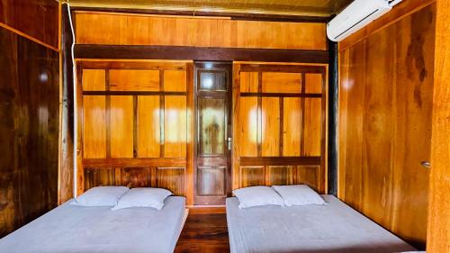 two beds in a room with wooden walls at Homestay Yến Long in Hữu Lũng