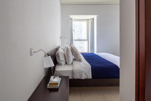 a bedroom with a bed with a blue blanket and a window at Frank Porter - Marina Heights in Dubai