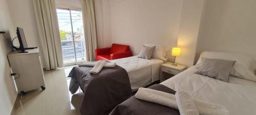 una habitación de hotel con 2 camas y una silla roja en DELFINA suites 3A en La Rioja