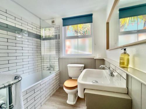 a white bathroom with a toilet and a sink at Farthing Cottage…cute ‘n’ cosy! in Kingsbridge