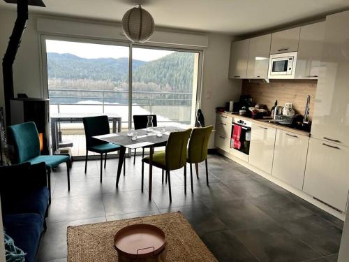 une cuisine et une salle à manger avec une table et des chaises dans l'établissement Appartement Neuf VUE LAC 6/8pers, à Gérardmer