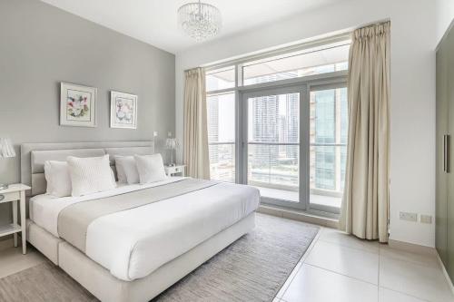 a white bedroom with a large bed and a large window at Frank Porter - The Lofts in Dubai