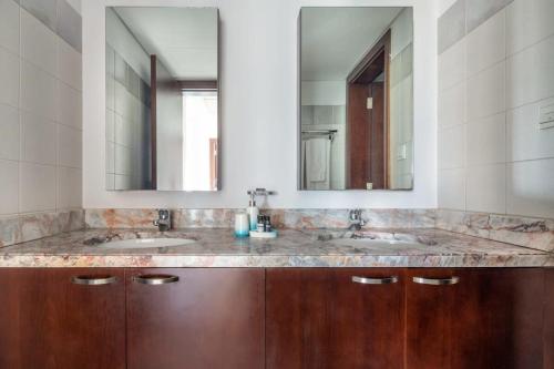 a bathroom with two sinks and two mirrors at Frank Porter - Marina Tower in Dubai