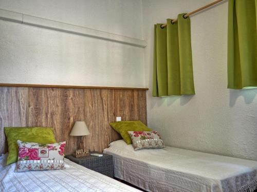 deux lits dans une chambre avec des rideaux verts dans l'établissement Prime Rose, à Saint-Aygulf