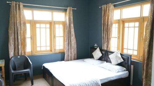 1 dormitorio con 1 cama, 2 ventanas y 1 silla en Green Resort, en Rājbāgh