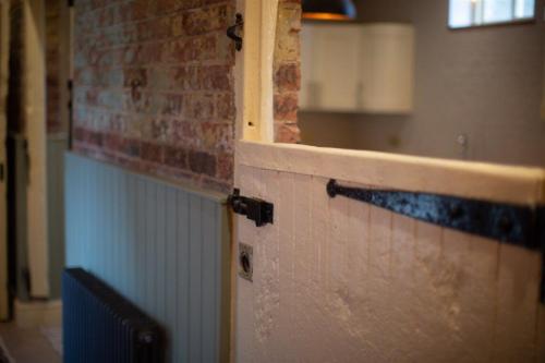 - une porte dans une pièce dotée d'un mur en briques dans l'établissement The Stables, à Longwitton
