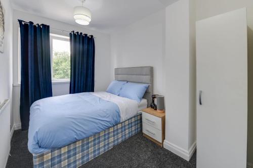 Schlafzimmer mit einem Bett und einem Fenster mit blauen Vorhängen in der Unterkunft Remarkable 3-Bed House in Middleton Manchester in Manchester