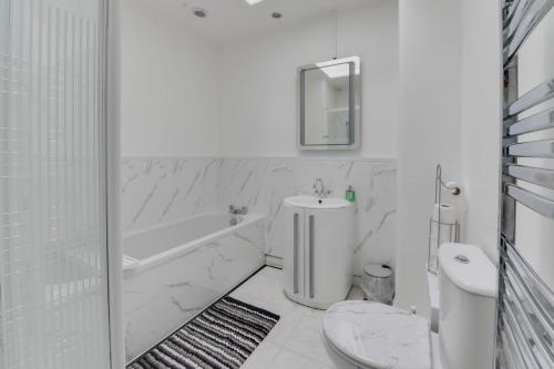 y baño blanco con aseo, bañera y lavamanos. en Remarkable 3-Bed House in Middleton Manchester, en Mánchester