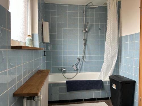 a blue tiled bathroom with a shower and a tub at Ferienhaus Morgenstern in Wilhelmshaven