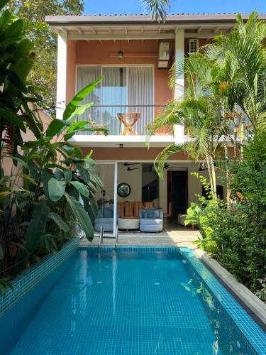 a villa with a swimming pool in front of a house at Angam Villas Colombo in Colombo