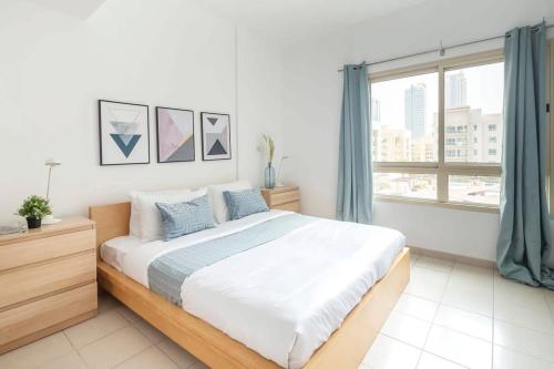 een witte slaapkamer met een groot bed en een raam bij Frank Porter - Al Samar in Dubai