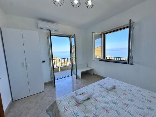 a bedroom with a bed and two large windows at Villa sul tramonto in Castel di Tusa