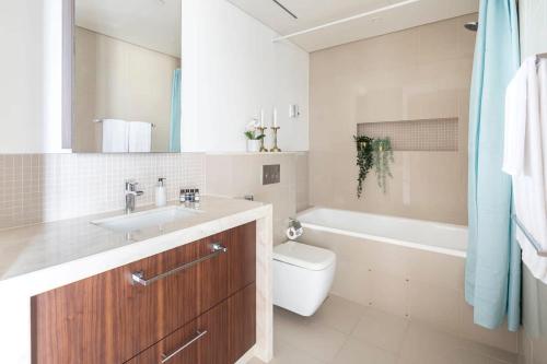 a bathroom with a sink and a toilet and a tub at Frank Porter - Boulevard Point in Dubai
