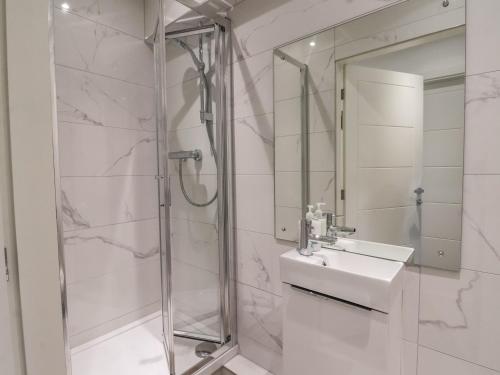een witte badkamer met een wastafel en een douche bij Wave Song in Hornsea