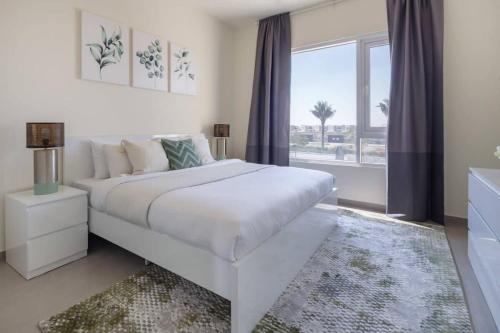 a white bedroom with a large bed and a window at Frank Porter - Urbana II in Dubai