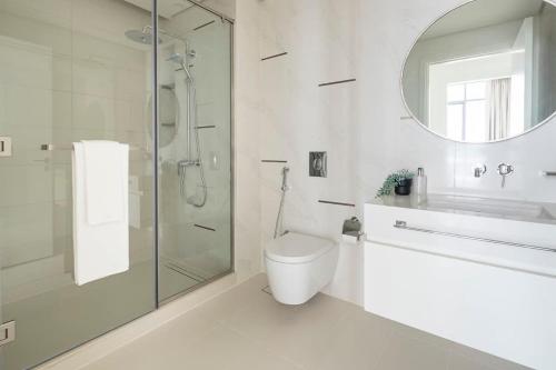 een badkamer met een douche, een toilet en een spiegel bij Frank Porter - Beach Vista Tower 1 in Dubai