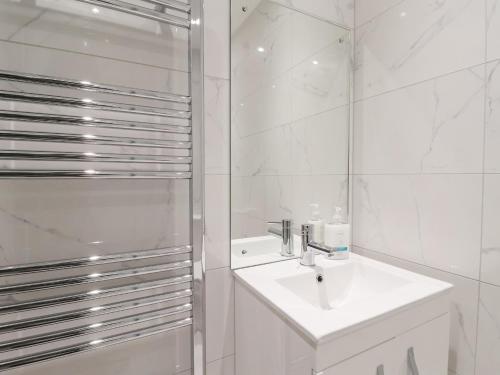 ein weißes Bad mit einem Waschbecken und einer Dusche in der Unterkunft Seashell in Hornsea