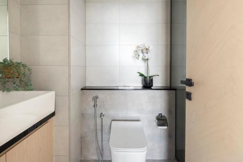 a bathroom with a toilet and a vase with flowers at Frank Porter - Binghatti Avenue in Dubai
