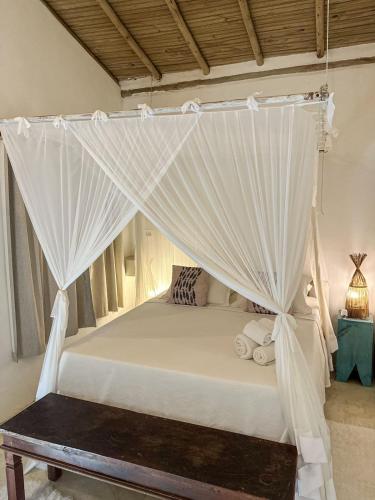 a bed with white mosquito netting in a room at Casa da Glória Trancoso - Pousada Boutique in Trancoso