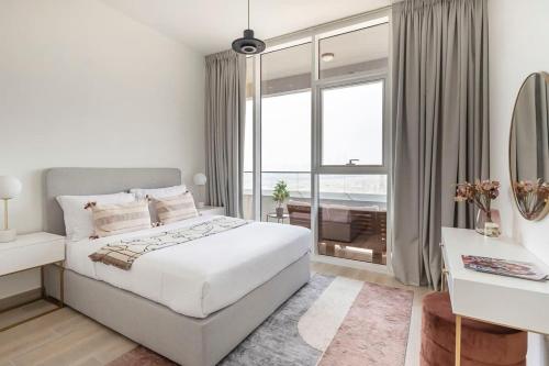 a white bedroom with a bed and a large window at Frank Porter - Bloom Tower in Dubai