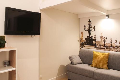 a living room with a couch and a tv on the wall at Cosy love nest near Gare de l'Est in Paris