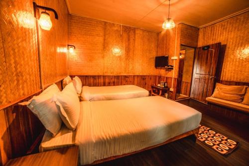 um quarto com 2 camas num quarto com paredes de madeira em The Basnett Croft em Gangtok