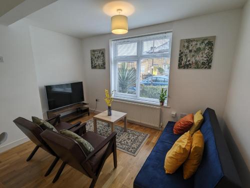 sala de estar con sofá azul y sillas en Fantastic 3-Bedroom House in London en Morden