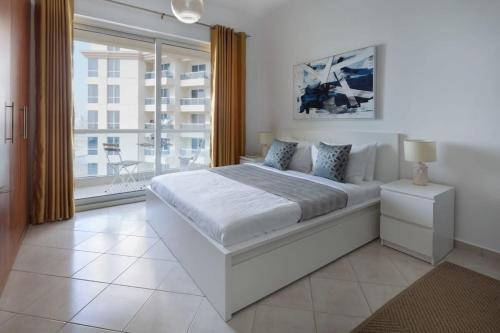 a white bedroom with a large bed and a window at Frank Porter - Damac Crescent A in Dubai