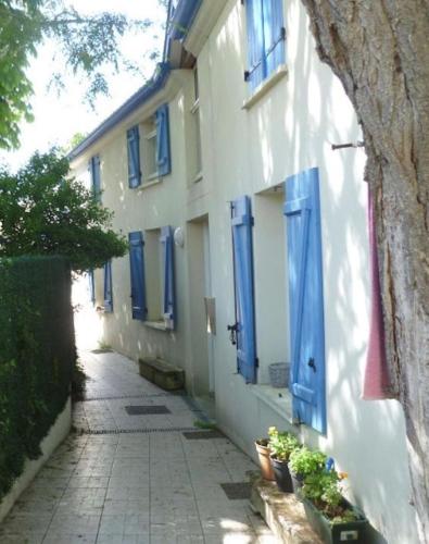 un vicolo con persiane blu su un edificio bianco di A -15min à Vélo du vieux Port La Rochelle 4 ad Aytré