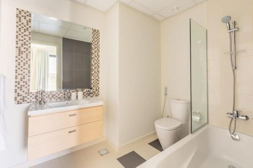 a bathroom with a tub and a toilet and a mirror at Frank Porter - Damac Sycamore in Dubai
