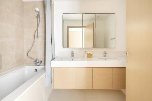 uma casa de banho com um lavatório, um espelho e uma banheira em Frank Porter - Creek Horizon Tower 2 em Dubai