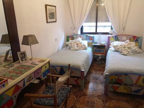 - une chambre avec 2 lits, une table et une fenêtre dans l'établissement La Casa del Artista, à Altea
