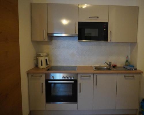 a kitchen with white cabinets and a stove and a microwave at Appartements Fritzhof in Kirchberg in Tirol