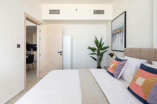 Dormitorio blanco con cama blanca grande y almohadas coloridas en Frank Porter - Binghatti Avenue, en Dubái