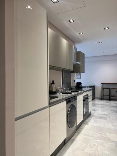 a kitchen with white cabinets and a washer and dryer at Les Joyeux Luxury Suites & Appart in Casablanca