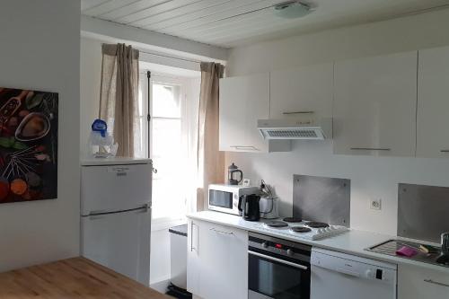 Il comprend une cuisine blanche équipée d'une cuisinière et d'un four micro-ondes. dans l'établissement Charming family nest in the heart of Chamonix, à Chamonix-Mont-Blanc