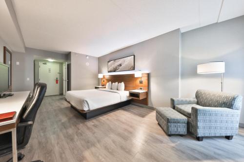 a hotel room with a bed and a desk and a chair at Admiral Inn Mississauga in Mississauga