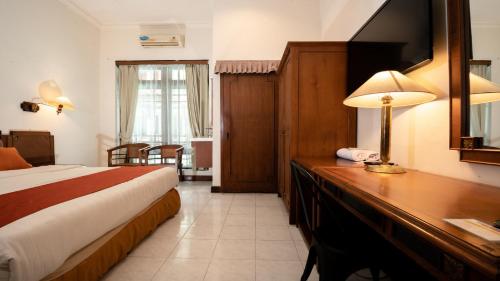 a hotel room with a bed and a desk with a lamp at HOTEL SAPTA GRIA in Jetis