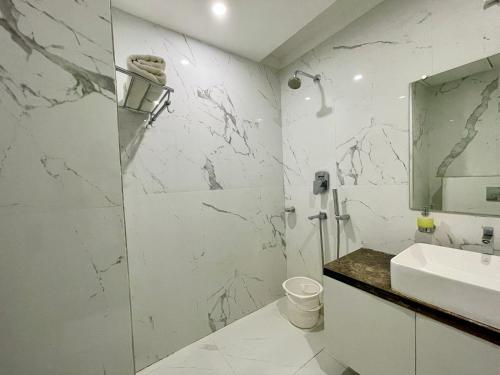 a white bathroom with a sink and a mirror at Hotel TBS - all-rooms-sea-view, Swimming-pool, fully-air-conditioned-hotel with-lift-and-parking-facility breakfast-included in Puri