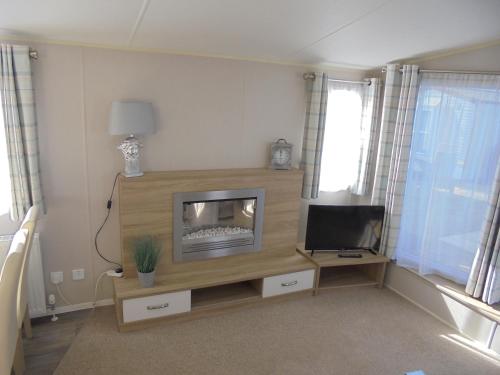 a living room with a fireplace and a tv at Golden Anchor Parkstone 6 Berth, Central heated in Chapel Saint Leonards