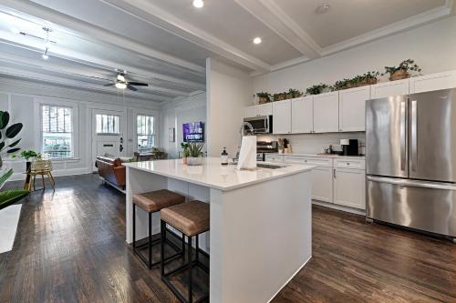 uma cozinha com armários brancos e uma ilha de cozinha com bancos de bar em Greenhouse Uptown em Dallas