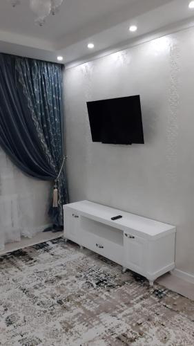 sala de estar blanca con TV en la pared en уютная 3 комнатная в центре города, en Shymkent