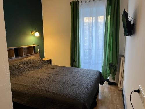 a bedroom with a bed and a window with green curtains at Ludotel in Belley