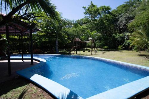 una gran piscina azul junto a un parque infantil en Tortuga House Playa Avellanas, en Playa Avellana